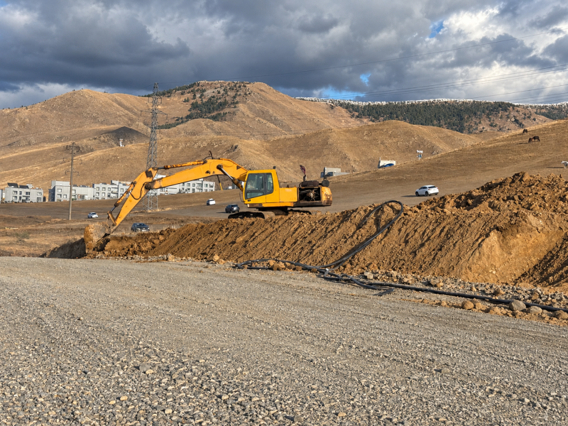 Excavator Under Stormy Hills